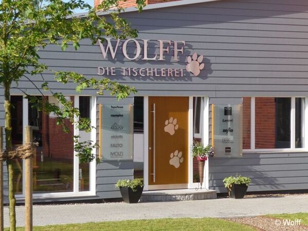 Eingangsbereich einer modernen Tischlerei mit Holzfassade und dekorativen Pfotenabdrücken.