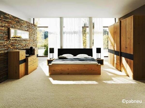 Modernes Schlafzimmer mit Holzmöbeln, großem Bett und Panoramafenstern im Tageslicht.