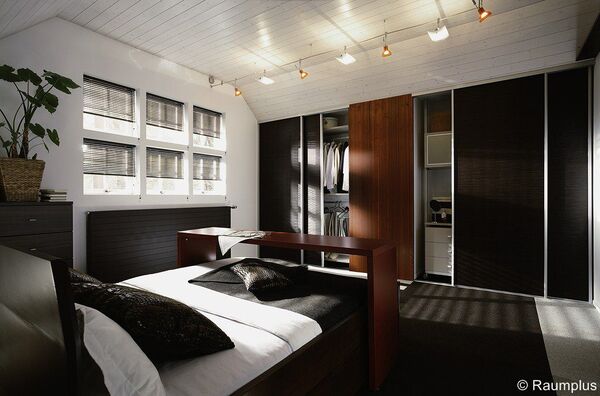 Modernes Schlafzimmer mit großem Kleiderschrank, stilvoller Beleuchtung und dekorativen Details.