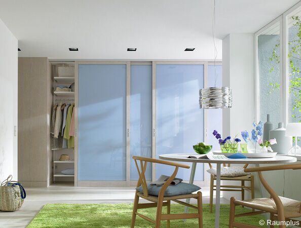 Heller, moderner Wohnraum mit Schiebetürenschrank, Essbereich und großem Fenster.